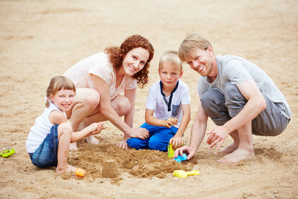 Glückliche Familie spielt im Familienurlaub am Strand im Sommer